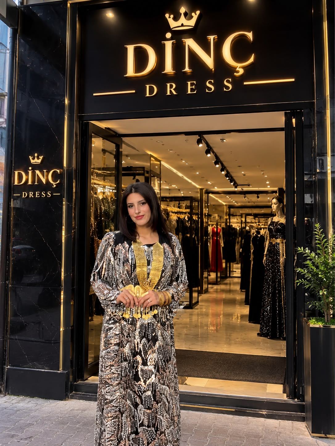 Dinç Dress Dörtyol mağaza vitrini önünde yöresel abiye ile poz